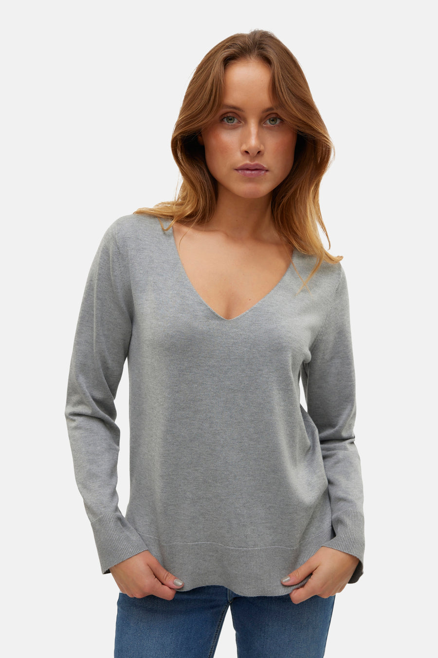 Pull à col en V gris de VERO MODA, porté par un mannequin aux cheveux longs.