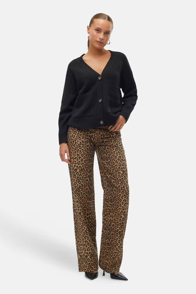 Cardigan noir de Vero Moda, avec poches plaquées et boutons marron, porté sur un pantalon léopard.
