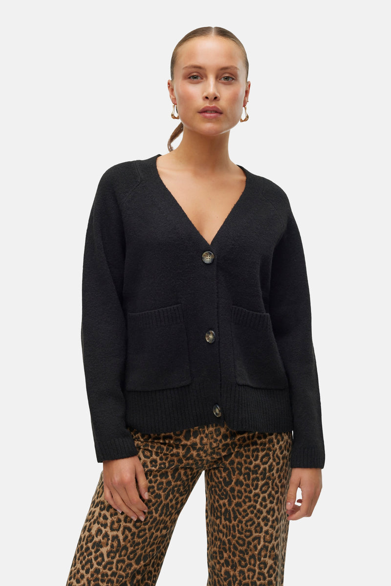 Cardigan noir de VERO MODA, porté avec un pantalon à motif léopard et des boucles d'oreilles dorées.