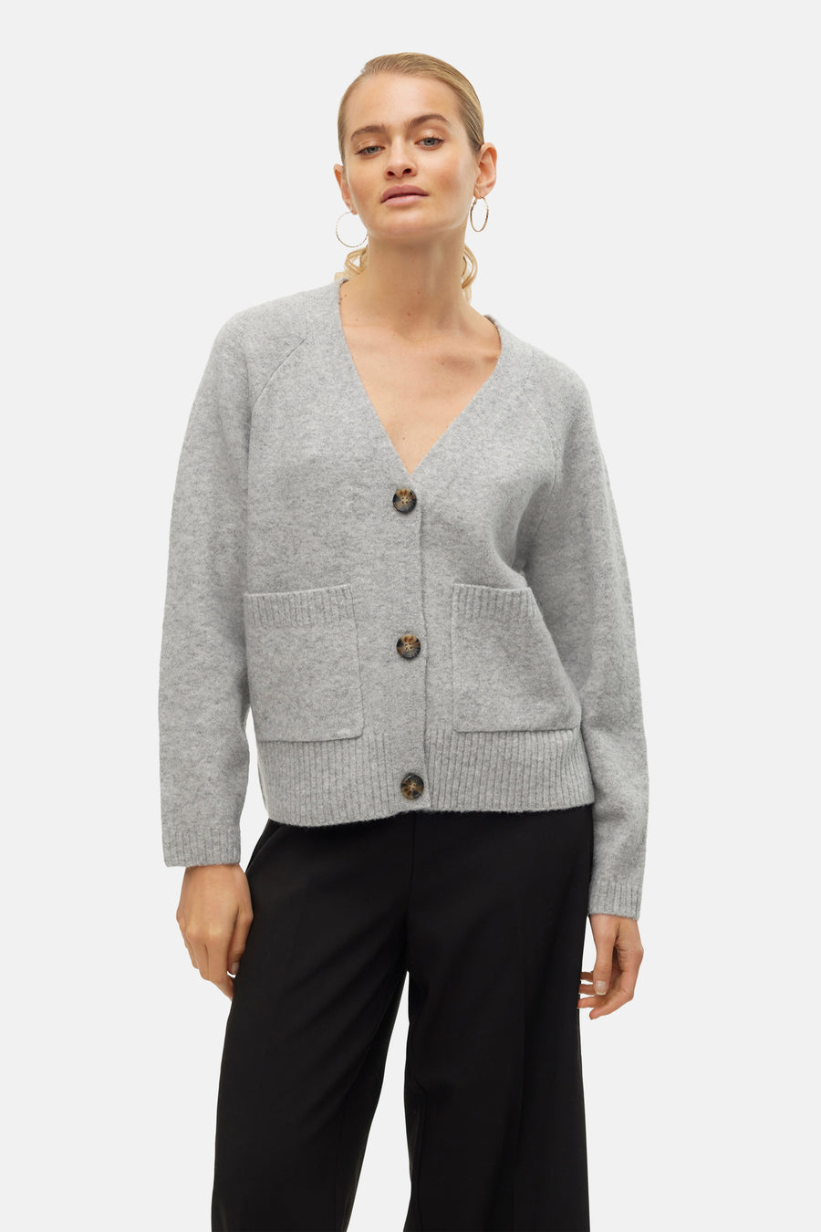 Cardigan gris de VERO MODA, porté avec un pantalon noir ample et des boucles d'oreilles dorées.
