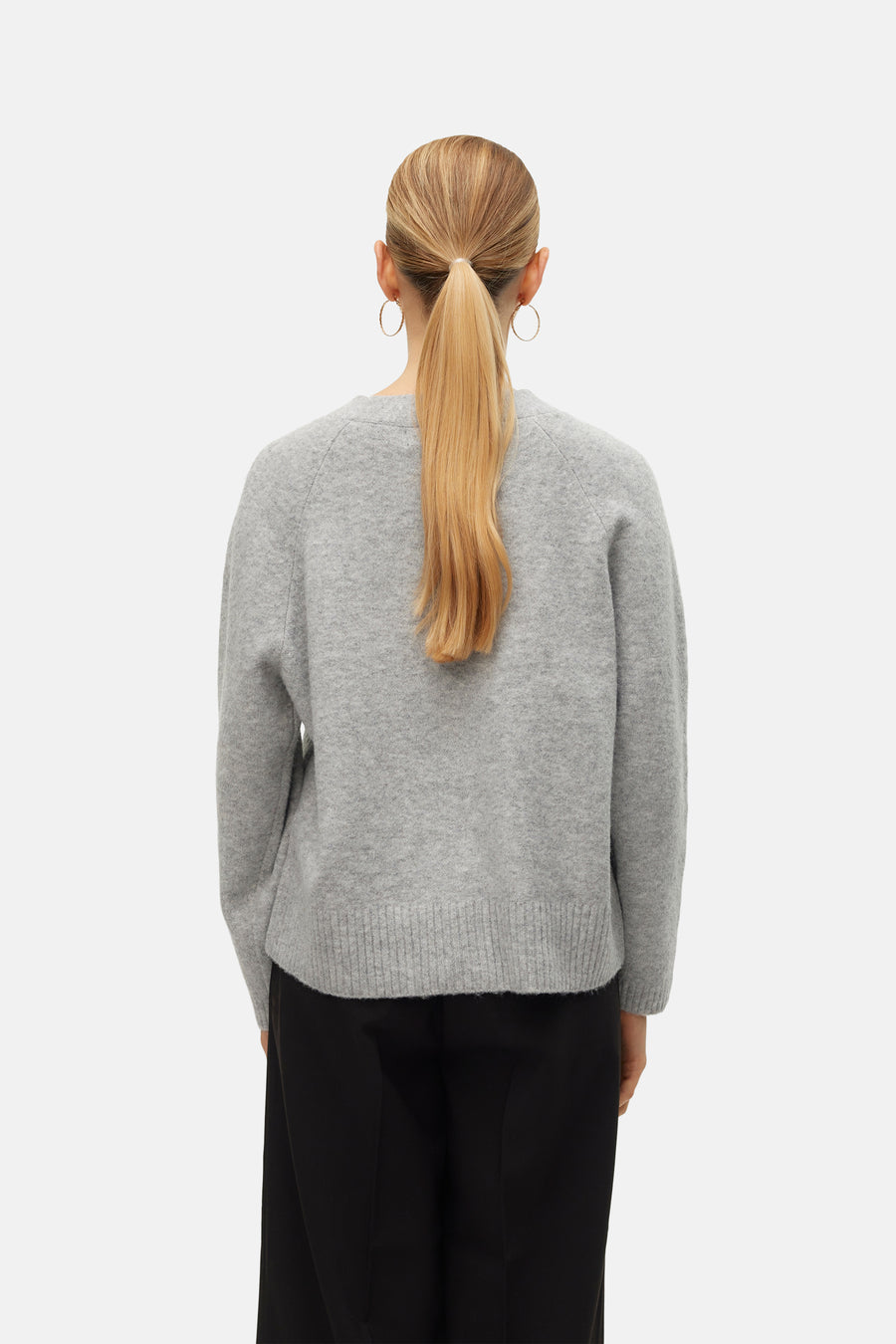 Cardigan gris en maille de VERO MODA, porté avec un pantalon noir et des boucles d'oreilles dorées, vue de dos.