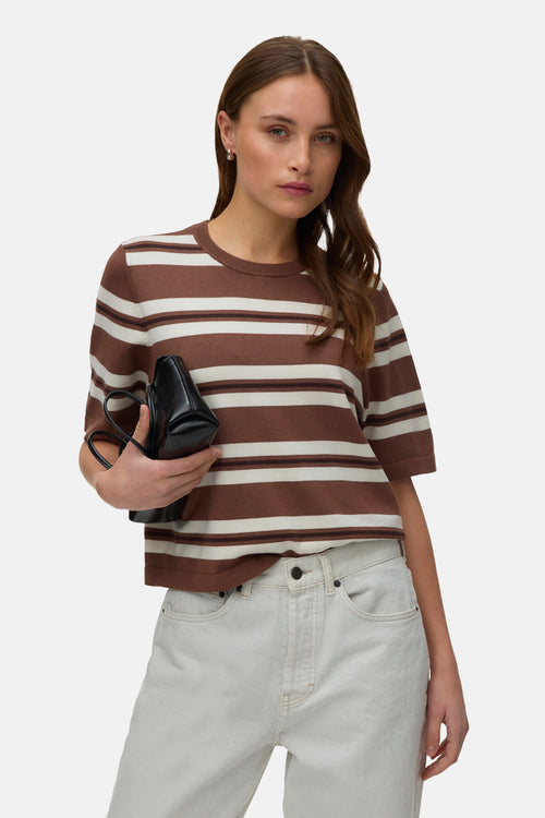 Cocoa brown striped O-neck pullover with cream and dark brown horizontal bands, short sleeves, ribbed trim, worn with light jeans and black clutch in lifestyle front view