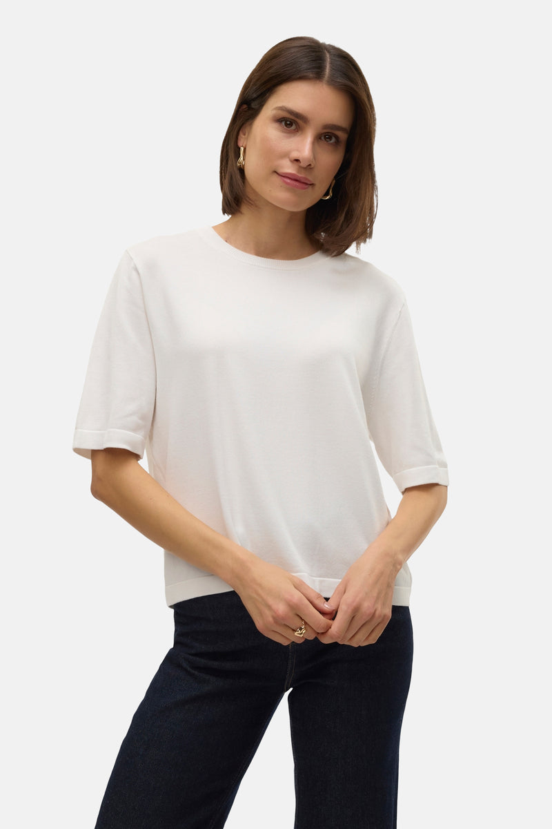 Witte ronde nekpull van VERO MODA, gedragen met een donkergroene broek en zwarte lederen laarzen.
