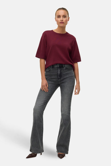 Pull à col rond bordeaux de Vero Moda, porté avec un jean évasé gris et des escarpins marron.