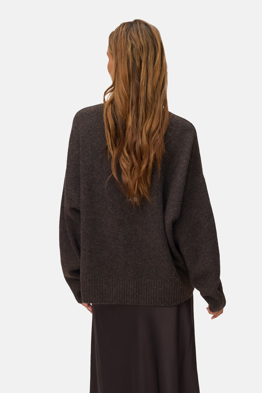 Chocolate brown oversized knit sweater with ribbed hem and cuffs, back view on model wearing dark skirt