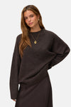 Chocolate brown oversized knit sweater with ribbed hem and cuffs, worn by model with gold pendant necklace, front view