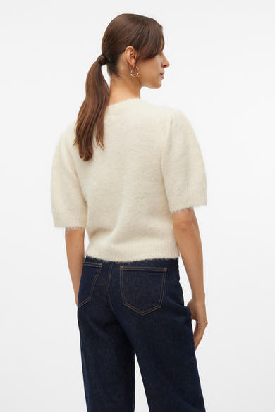 Pull à col rond écru de VERO MODA, manches courtes bouffantes et texture duveteuse, porté avec un jean taille haute.
