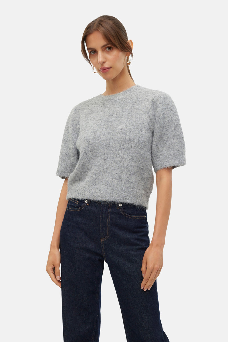 Pull à col rond gris de VERO MODA, porté avec un jean taille haute bleu foncé.
