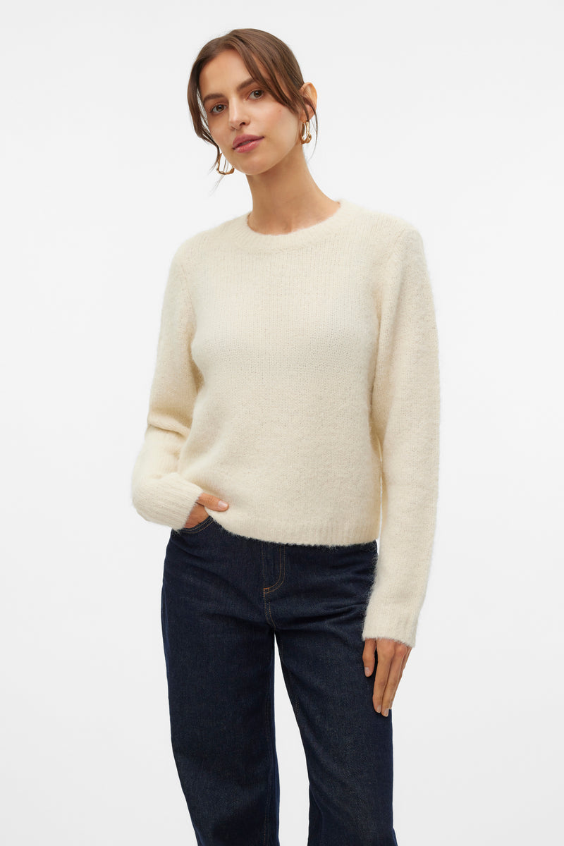 Pull à col rond écru de VERO MODA, porté avec un jean taille haute et des boucles d'oreilles dorées.