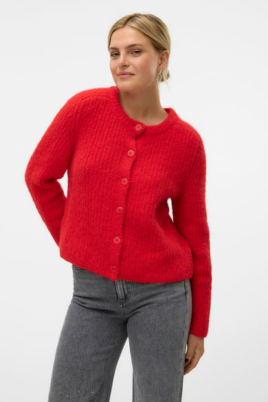 Gilet rouge en maille du VERO MODA, avec des boutons, porté avec un jean gris.
