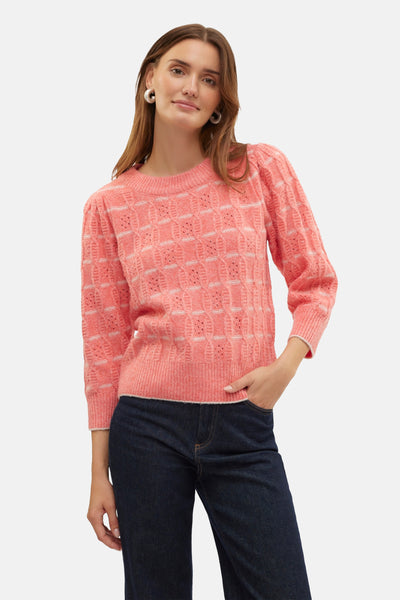 Koraalkleurige trui met ronde hals van VERO MODA® met ajourpatroon, gedragen met een donkere jeans.