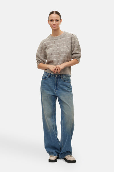 Beige ronde hals trui van VERO MODA®, met ajourpatroon en pofmouwen, gedragen met een wijde blauwe jeans.