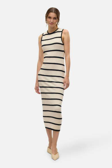 Robe rayée noire et écrue de Vero Moda, coupe moulante arrivant aux genoux, portée avec des mules beiges.
