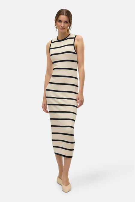 Robe rayée noire et écrue de Vero Moda, coupe moulante arrivant aux genoux, portée avec des mules beiges.
