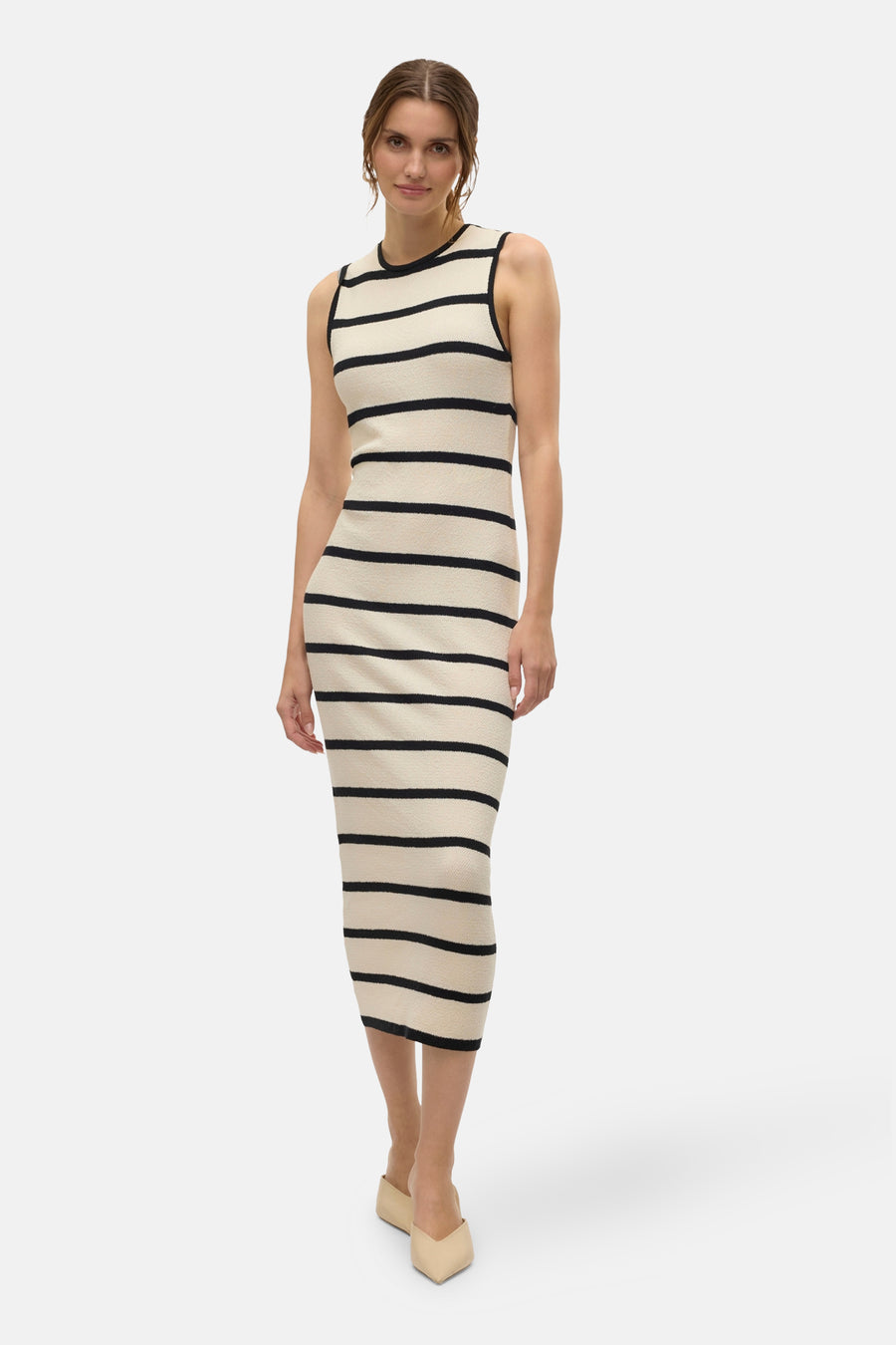 Robe rayée noire et écrue de Vero Moda, coupe moulante arrivant aux genoux, portée avec des mules beiges.
