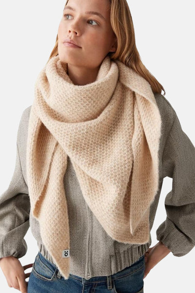 Écharpe beige OPUS en tricot texturé, portée avec un manteau gris et un jean.