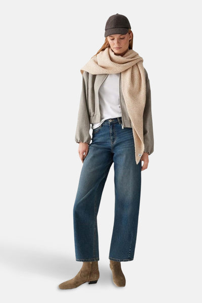 Écharpe beige d'OPUS, enveloppée autour du cou, avec une veste grise et un chapeau foncé.