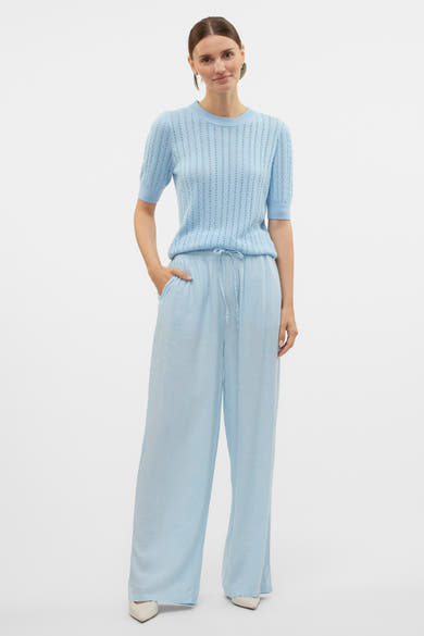 Pull à col rond bleu de VERO MODA, ajouré avec pantalon fluide assorti et chaussures à talons pointus.