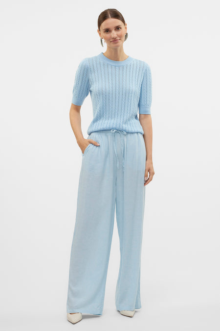 Pull à col rond bleu de VERO MODA, ajouré avec pantalon fluide assorti et chaussures à talons pointus.