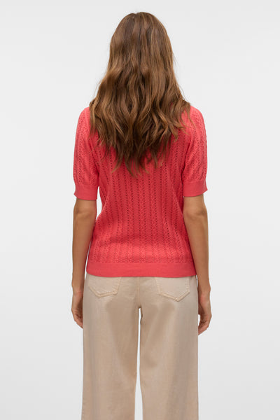 Koraalkleurige trui met ronde hals van VERO MODA, opengewerkt patroon, gedragen met een beige broek.