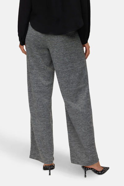 Grijze gemêleerde broek van VERO MODA, wijde pasvorm, gedragen met een zwarte blouse en stippenpumps.