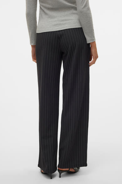 Pantalon noir à rayures verticales de VERO MODA, porté avec un haut gris à manches longues et des chaussures à talons noirs.