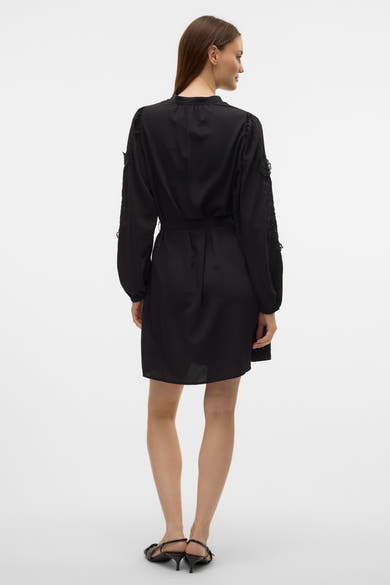 Zwarte jurk van VERO MODA met bloemendessins op de lange mouwen, van achteren gezien.
