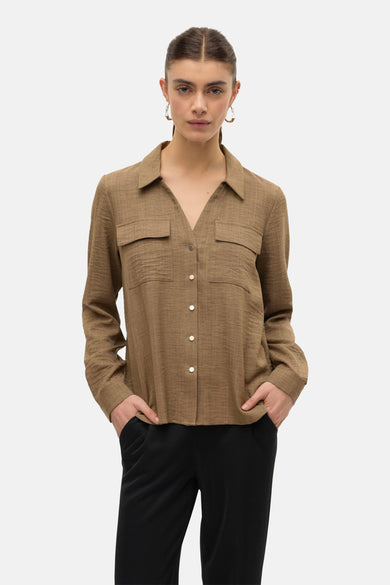 Bruine blouse met lange mouwen van VERO MODA, met borstzakken en gouden knopen, gedragen met een zwarte broek.
