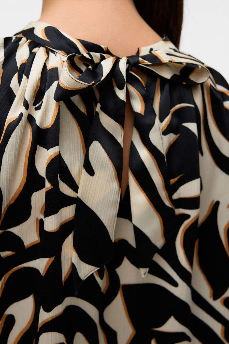 Multikleed van VERO MODA, met een abstract patroon in zwart, beige en bruin, decoratieve strik bij de halslijn aan de achterkant.