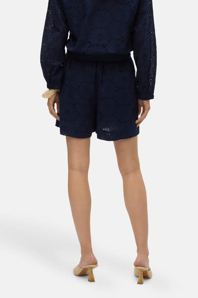 Short bleu ajouré de VERO MODA, porté avec un haut assorti et des mules à talons.
