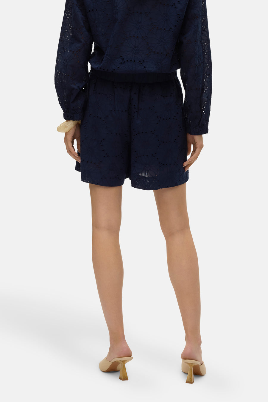 Short bleu ajouré de VERO MODA, porté avec un haut assorti et des mules à talons.
