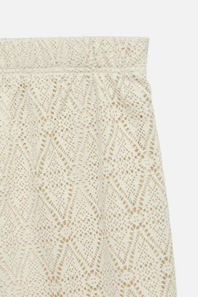 Short beige ajouré de VERO MODA®, motif losanges, texture crochetée, sur fond uni clair, détail de la ceinture élastiquée.
