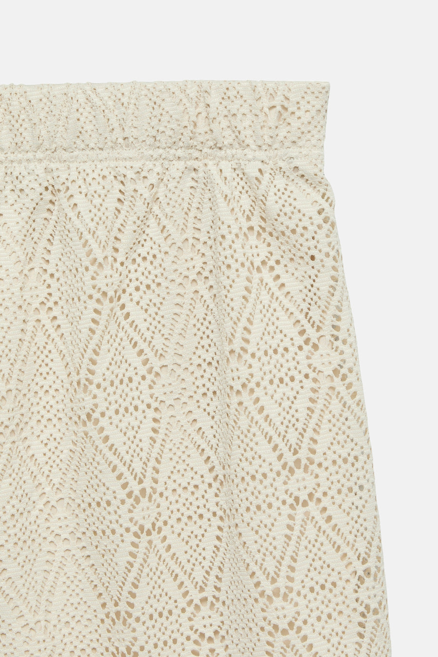 Short beige ajouré de VERO MODA®, motif losanges, texture crochetée, sur fond uni clair, détail de la ceinture élastiquée.
