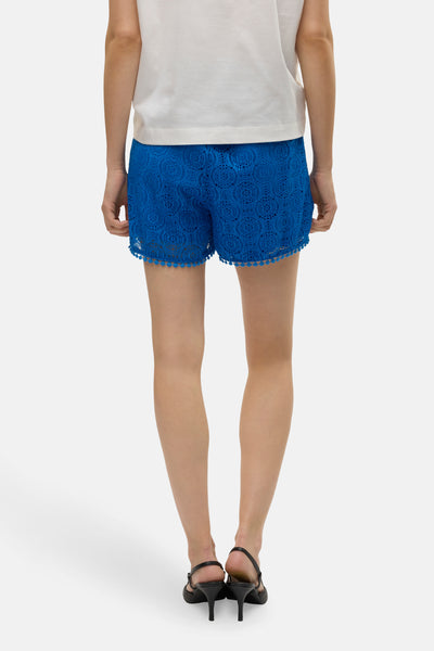 Kort blauw broekje van VERO MODA, met uitgesneden details en een pomponrand.