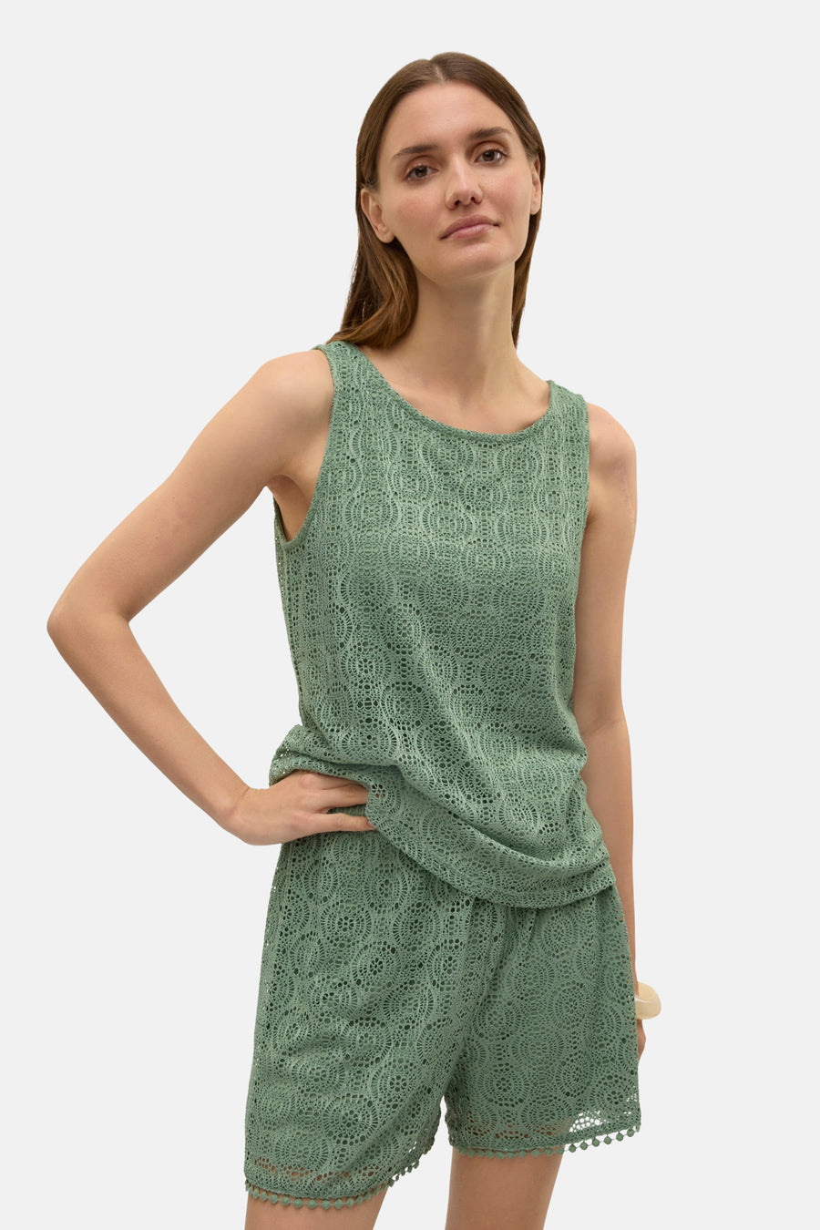 Groen kanten hemdje van VERO MODA, met een open textuur en een gedrapeerde zoom, gedragen met een bijpassende korte broek.