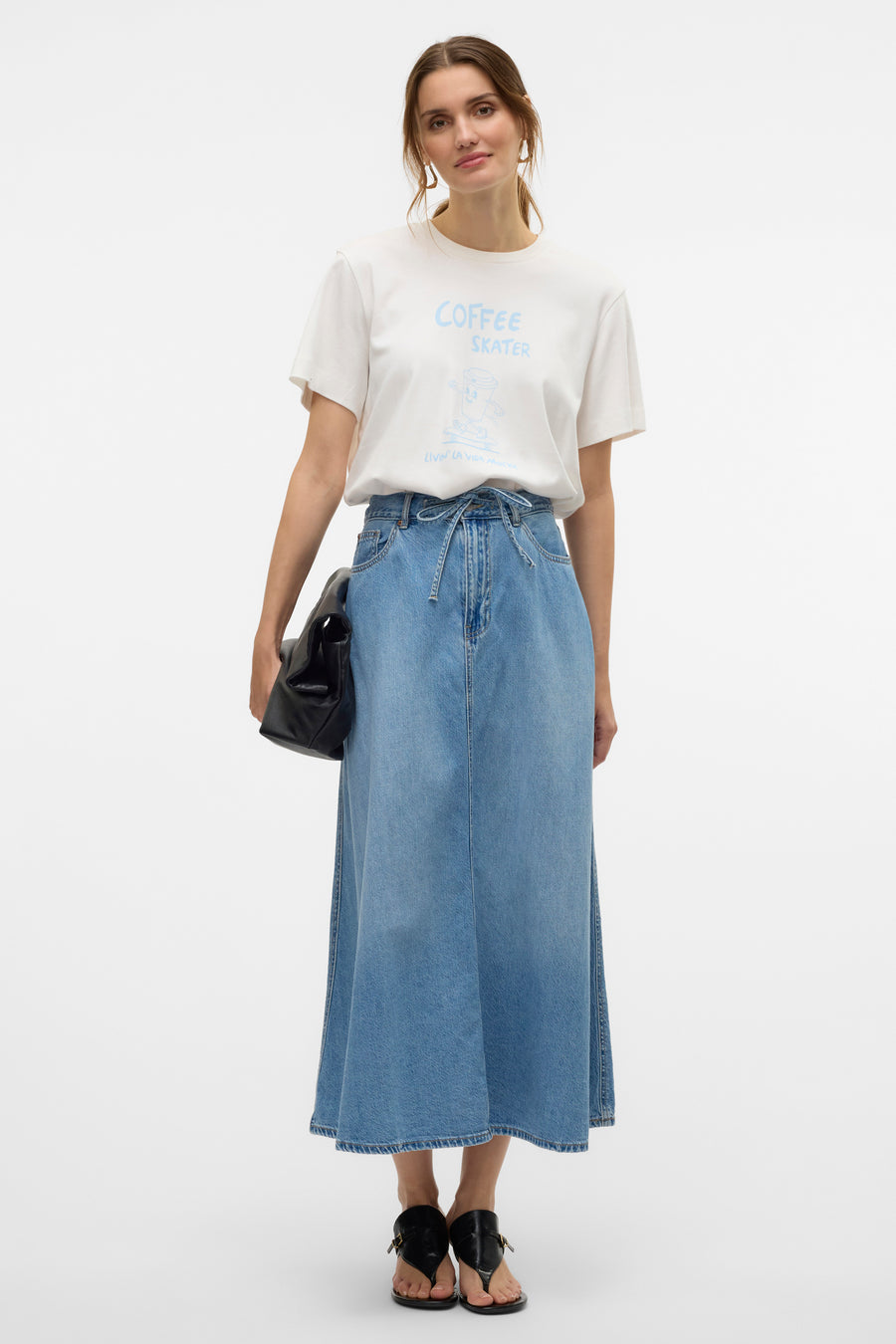 T-shirt blanc à manches courtes de VERO MODA®, imprimé Coffee Skater, porté avec une longue jupe en jean.
