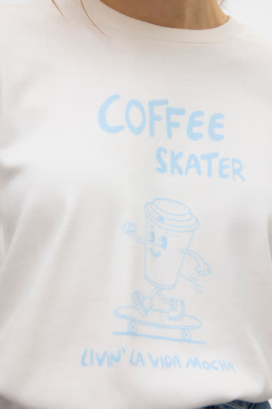 T-shirt à manches courtes blanc de VERO MODA® avec un imprimé humoristique de tasse à café sur un skate.