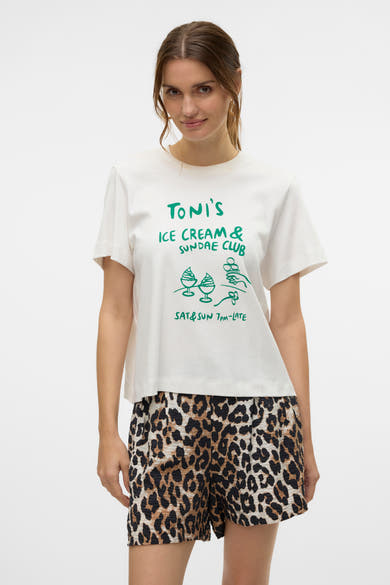 T-shirt à manches courtes blanc de VERO MODA® avec imprimé graphique vert, porté avec un short léopard.

