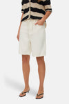 Short écru de VERO MODA, porté avec un haut rayé et des chaussures à talons.
