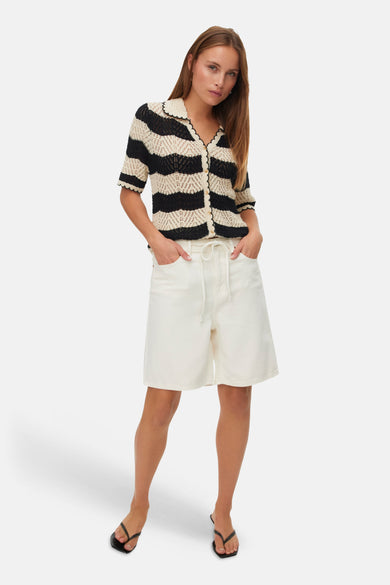 Short écru de VERO MODA, porté avec un haut rayé noir et blanc et des sandales noires.