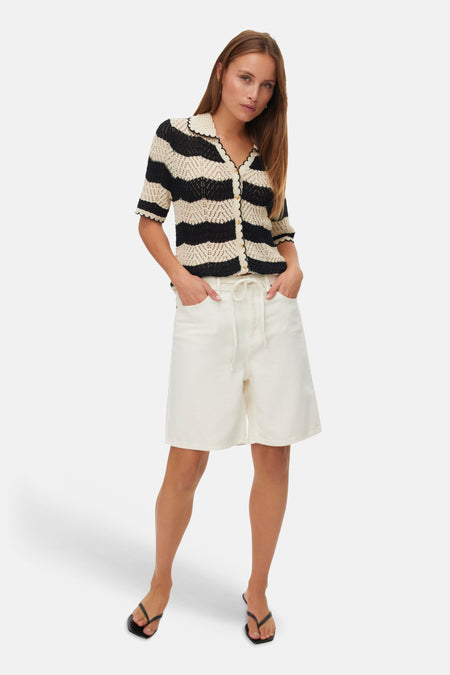 Short écru de VERO MODA, porté avec un haut rayé noir et blanc et des sandales noires.