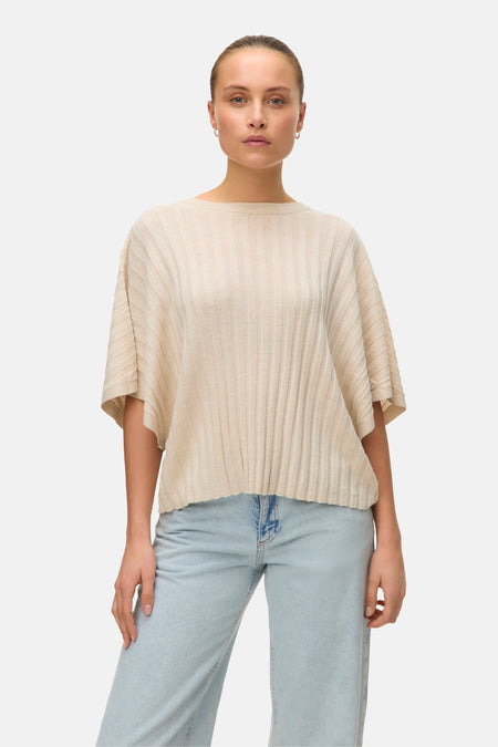 Pull beige de VERO MODA® avec une texture côtelée, porté avec un jean décontracté.