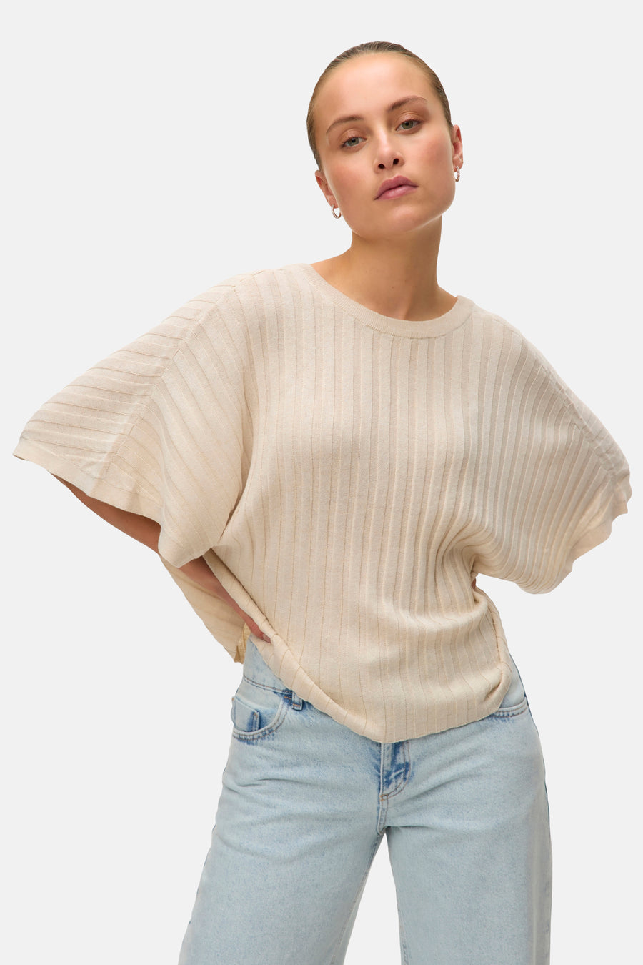 Pull beige côtelé de VERO MODA®, porté avec un jean taille haute bleu clair.
