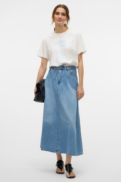 Jupe longue en denim bleu moyen de VERO MODA®, avec ceinture à nouer et t-shirt blanc imprimé.
