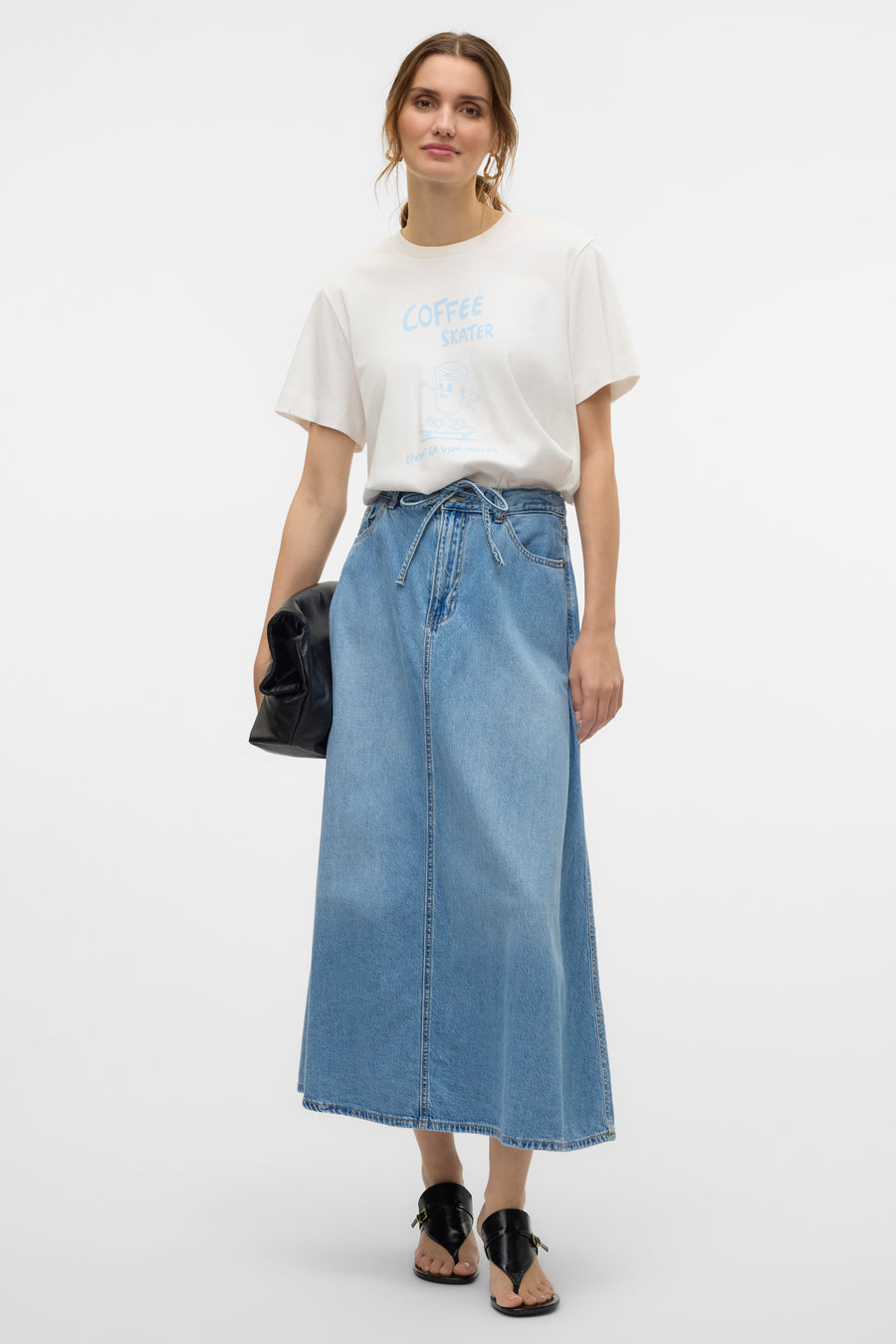 Jupe longue en denim bleu moyen de VERO MODA®, avec ceinture à nouer et t-shirt blanc imprimé.
