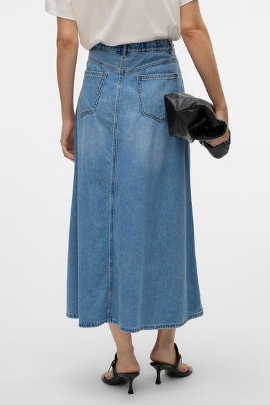 Middelblauwe lange spijkerrok van VERO MODA, van achteren gezien, met een zwarte clutch en sandalen met hak.