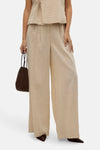 Pantalon beige de VERO MODA, ample et fluide, porté avec un haut assorti et un sac marron.
