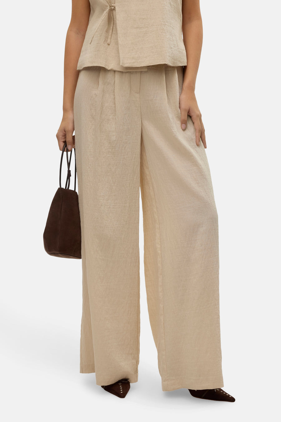 Pantalon beige de VERO MODA, ample et fluide, porté avec un haut assorti et un sac marron.
