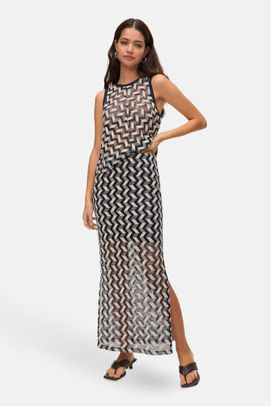 Blouse bleue sans manches de VERO MODA, à motif géométrique zigzag sur l'ensemble, portée avec une jupe assortie et des sandales.
