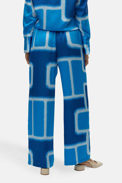 Blauwe broek met grafische print, van VERO MODA®, met rechte pasvorm en crèmekleurige schoenen.